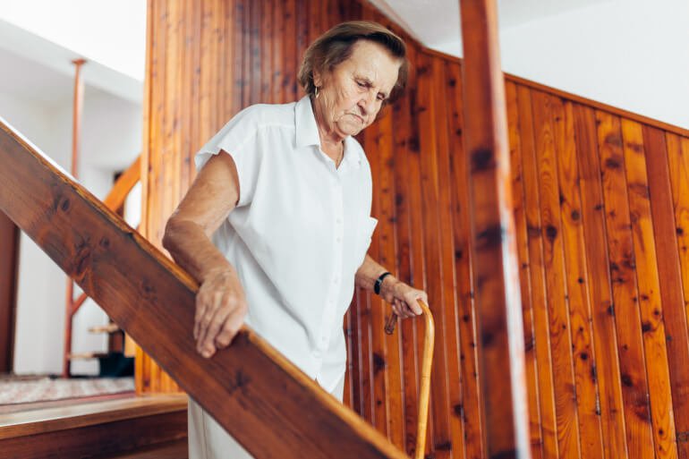 Ältere Frau geht Treppe hinunter