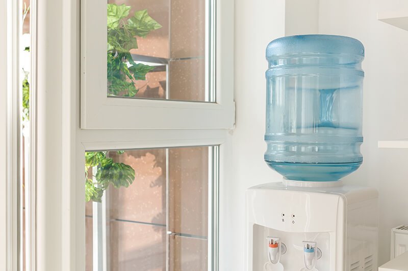 Wasserspender mit Wassertank neben Fenster